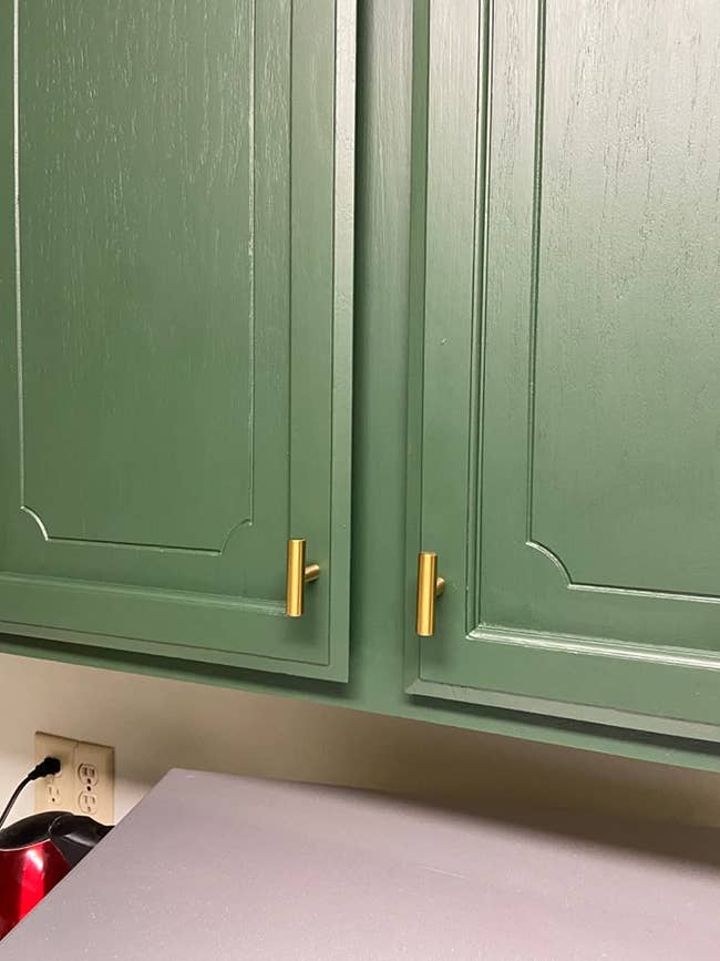 A green cabinet with the gold knobs
