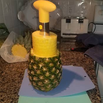 reviewer showing the pineapple corer pulling out the insides of pineapple