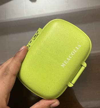 a reviewer holding a small green pill case 