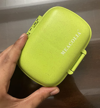a reviewer holding a small green pill case 