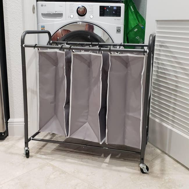 reviewer image of a three-bag hamper in front of a washer and dryer