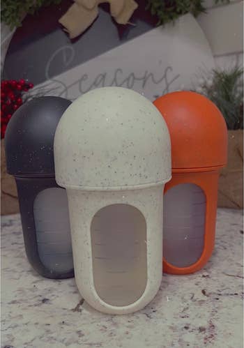 reviewer's three black, cream, and orange speckled silicone bottles