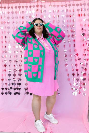 Model in a vibrant patterned pink and green cardigan with hearts