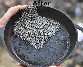 Model holding same cast iron skillet without food and chainmail scrubber on top of it labeled 