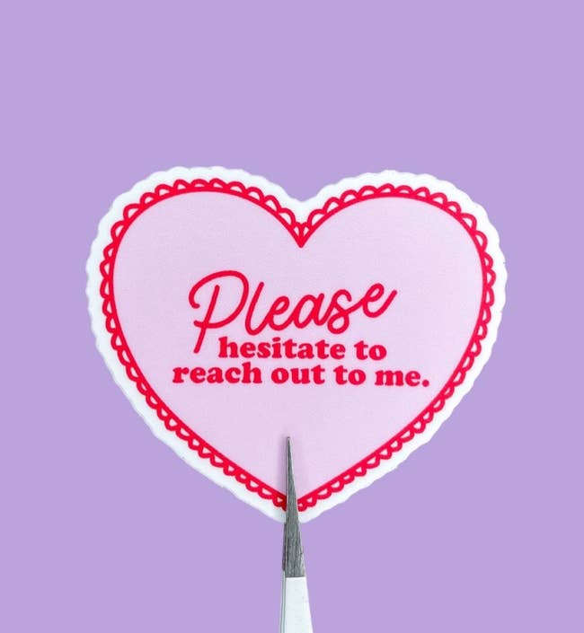 a small heart-shaped sticker with a red lace border and text in the center that reads 