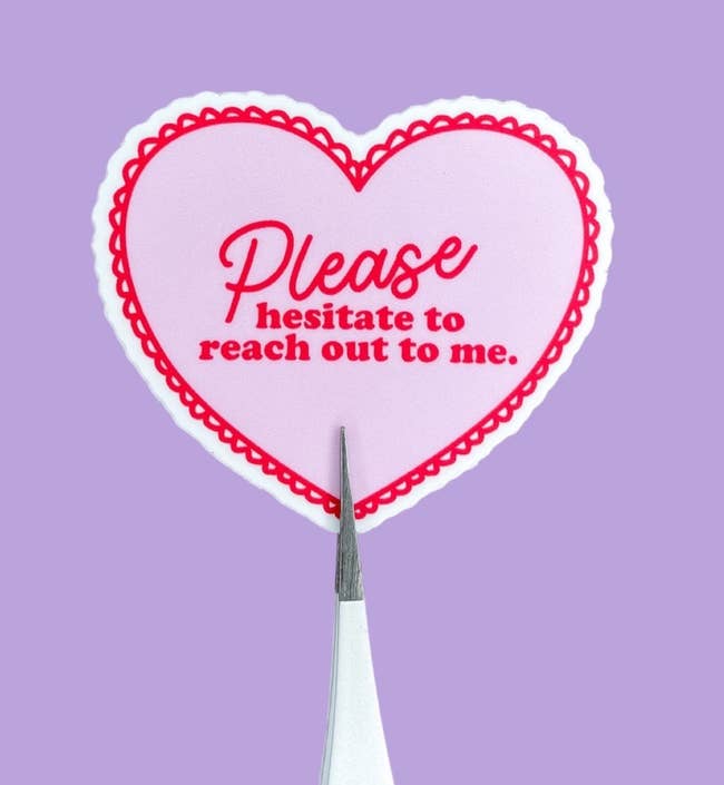 a small heart-shaped sticker with a red lace border and text in the center that reads 