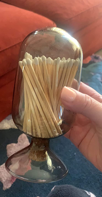 Reviewer holding black glass match holder with matches inside
