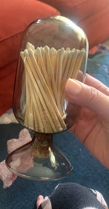 Reviewer holding black glass match holder with matches inside