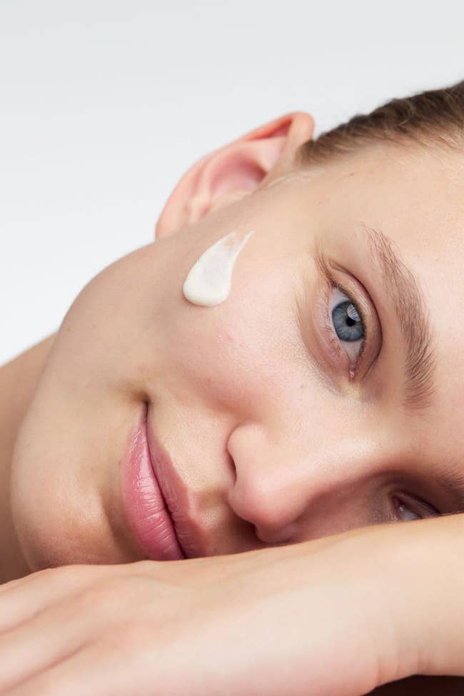 Close-up of a idiosyncratic with pick applied to their cheek, resting their caput connected their arm, promoting skincare successful a buying context