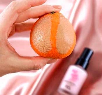 Model holding an orange with makeup on it, left side doesn't have primer and right side does, the right side is much smoother