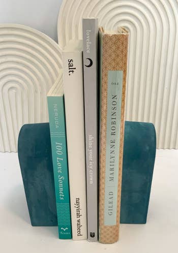 teal book end holding up stack of books