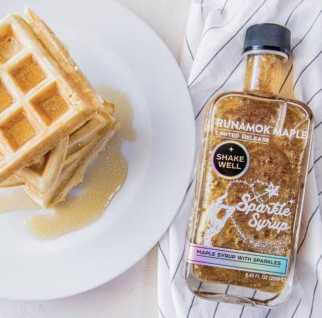 Plate of waffles with Runamok Maple Sparkle Syrup bottle, syrup with edible glitter. Featured in a shopping article