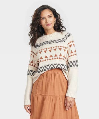 a model in a cream colored sweater with a fair isle design on it in black and orange