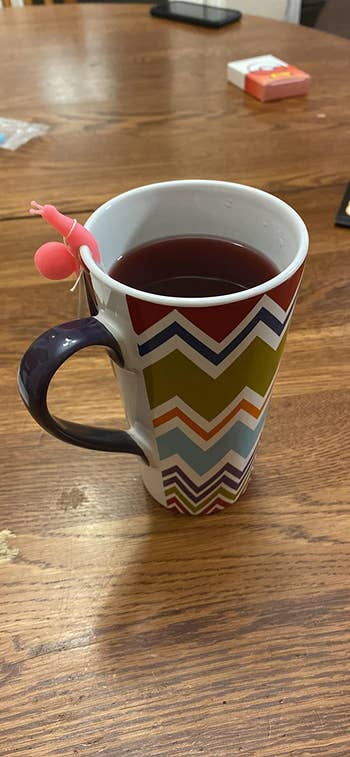 Reviewer's tea mug with a snail perched on the edge holding up the tea bag string