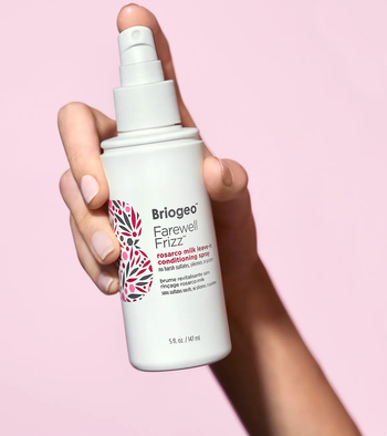 model holding the white bottle of leave-in conditioner