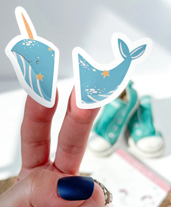 A close up of the whale sticker on a models fingers