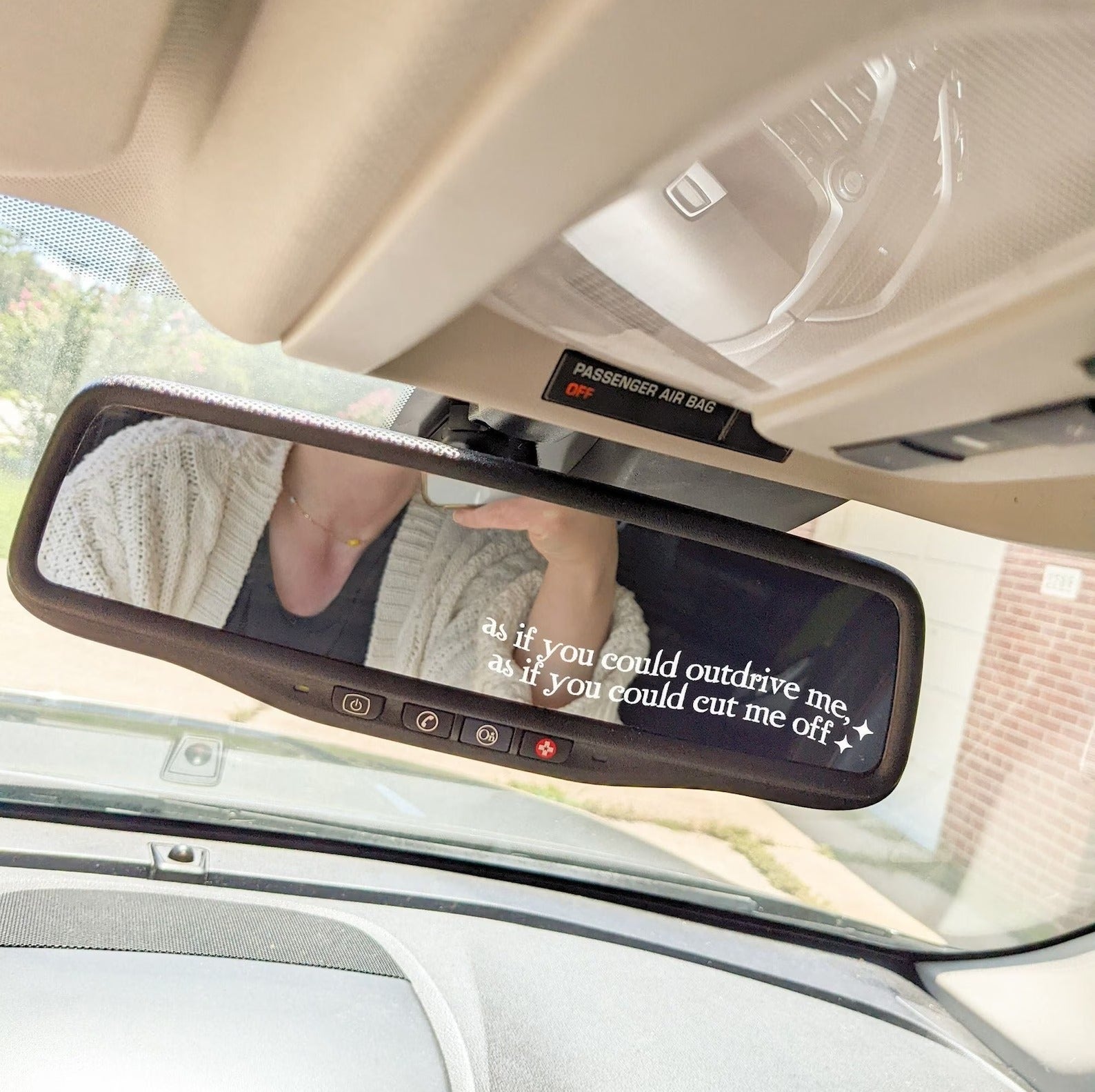 white sticker in corner of rearview mirror that says