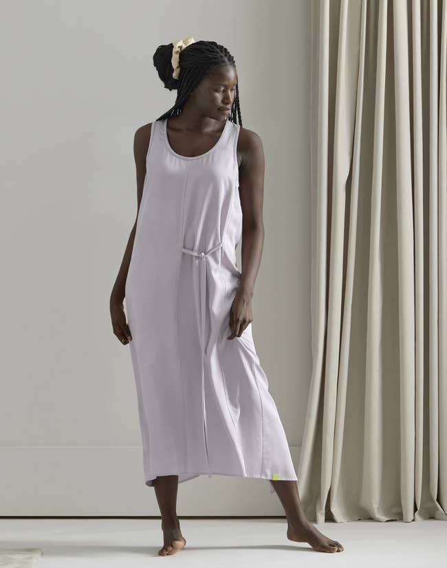Model in a pale purple sleeveless scoop neck maxi night dress with a tie string at the waist 