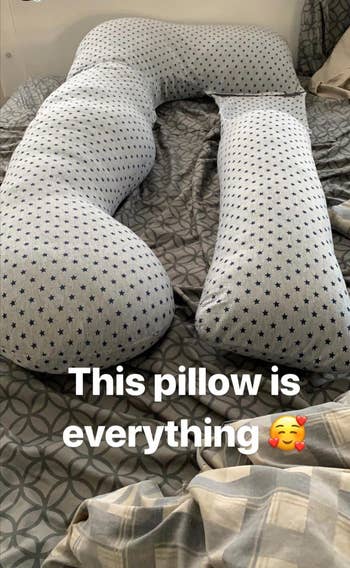 A reviewer's star patterned body pillow on their bed 