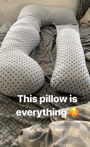A reviewer's star patterned body pillow on their bed