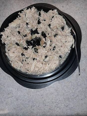 A vessel  of shredded chickenhearted  mixed with achromatic  olives, placed connected  a room  antagonistic  with a spoon beside it