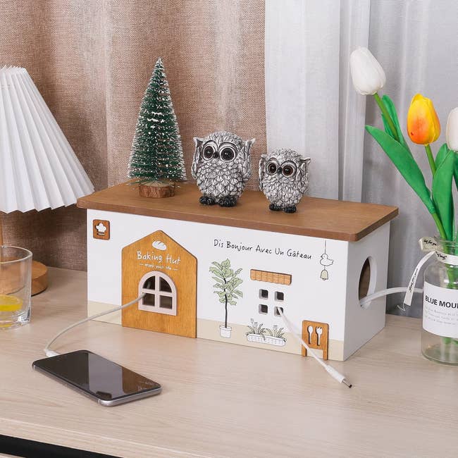 Owl figurines on a kitchen counter beside a miniature tree and a phone charging station with French text
