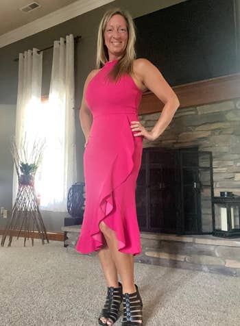 Reviewer in a sleeveless pink bodycon midi dress with asymmetrical hemline