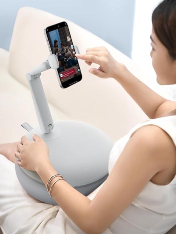 Person using a smartphone holder to watch content on their device comfortably