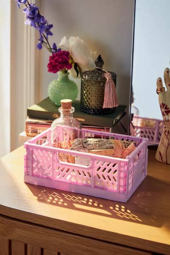 A lavender basket on a wooden surface containing various small items