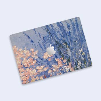 Laptop with a textured floral plan  connected  the cover, featuring pinkish  blossoms