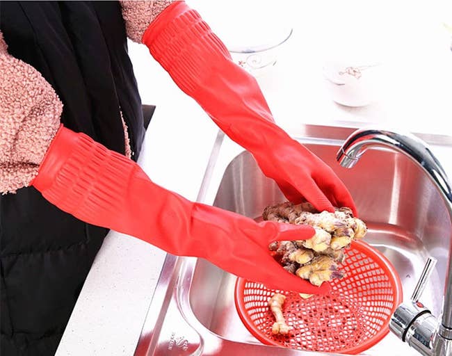person washing dishes with very long dishwashing gloves 