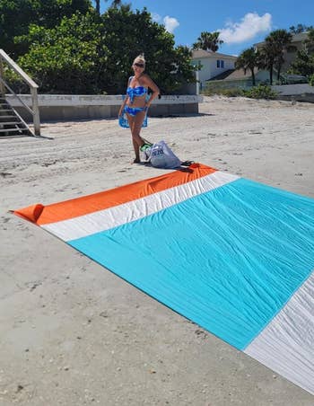 person connected  a formation  successful  a bluish  and achromatic  swimsuit adjacent  to a formation  container  and a large, colorful formation  blanket