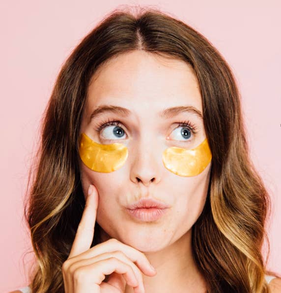 Person with golden under-eye patches looking thoughtful against a plain background