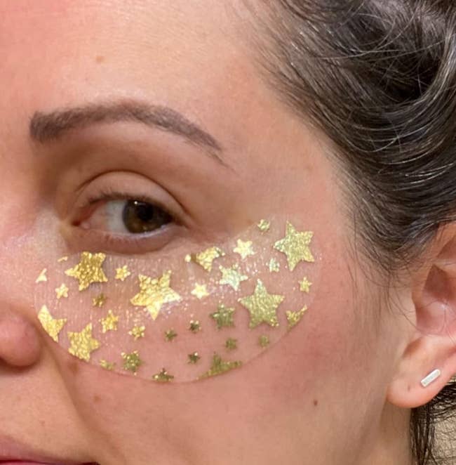 Reviewer with a transparent eye mask with glittery gold stars under their eye 