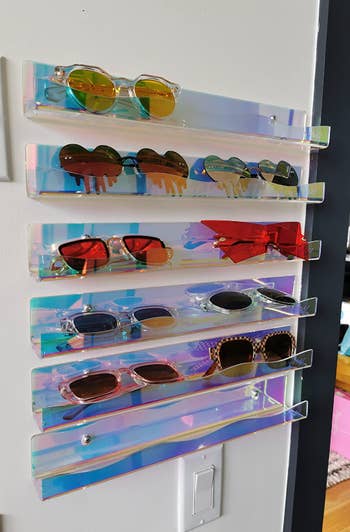 shelves holding up five rows of sunglasses and mounted on reviewer's wall 