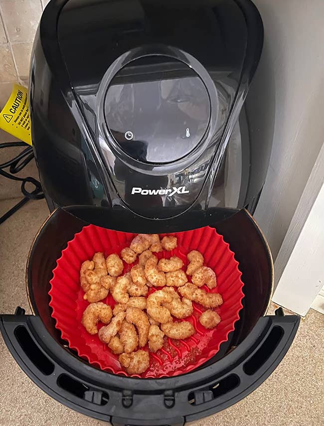 A red liner in an air fryer full of popcorn shrimp