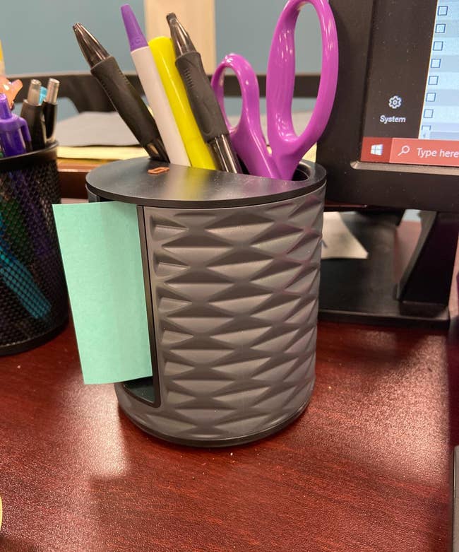 reviewer's post-it note dispenser holding blue post-its and pens, a highlighter, and scissors