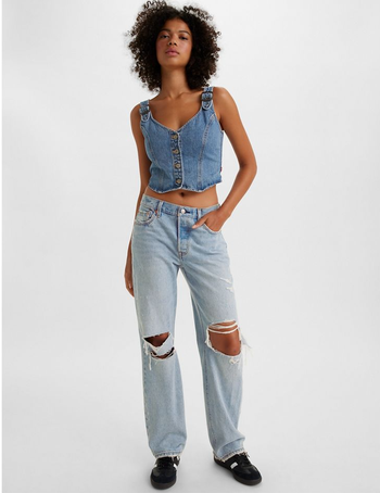 model wearing the ripped light blue version with a denim bustier top