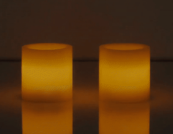 Video of two white flameless candles glowing on top of a table