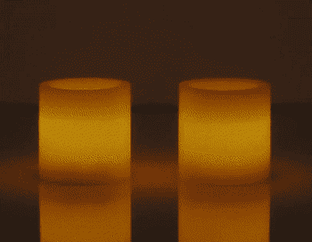 Video of two white flameless candles glowing on top of a table