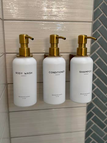 Three wall-mounted bottles labeled Body Wash, Conditioner, and Shampoo