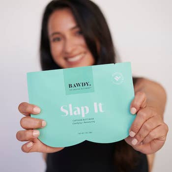 model holding up the teal mask packaging, which is shaped like a butt