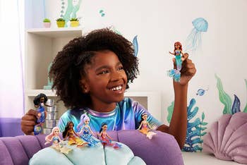 a child playing with mermaid dolls