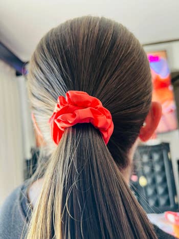 Person with ponytail wearing a scrunchie. The focus is on the hair accessory, ideal for casual or everyday wear, featured in a shopping article
