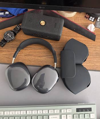 Wireless over-ear headphones, protective case, and a keyboard connected a table with a ticker and a Bluetooth talker nearby