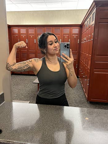 reviewer gym mirror selfie, flexing, wearing gray tank top
