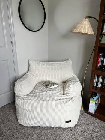 A cozy bean bag chair with a book and smartphone on it, placed in a well-organized room