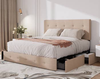 Stylish chamber with a beige upholstered retention bed, achromatic bedding, and bedside array with a vase of flowers
