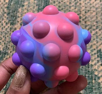 Reviewer holding pink and purple fidget ball