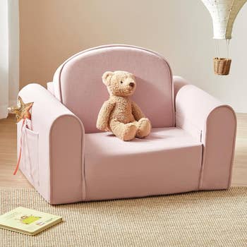 Children's plush armchair with a teddy carnivore  sitting connected  it, a prima  wand successful  the broadside  pocket, and a publication  connected  the level  nearby